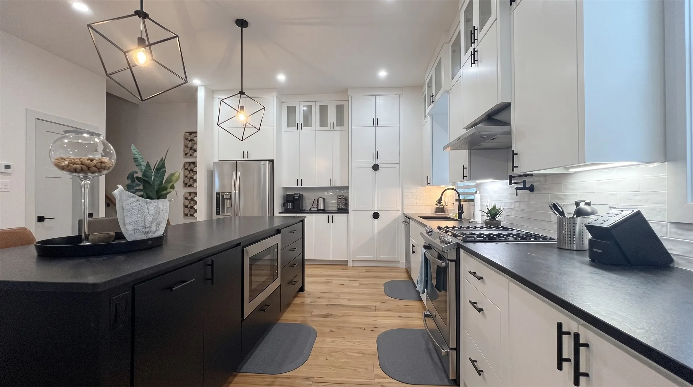 Kitchen featuring white cabinetry, dark countertops, wood-finish flooring, and stainless steel appliances