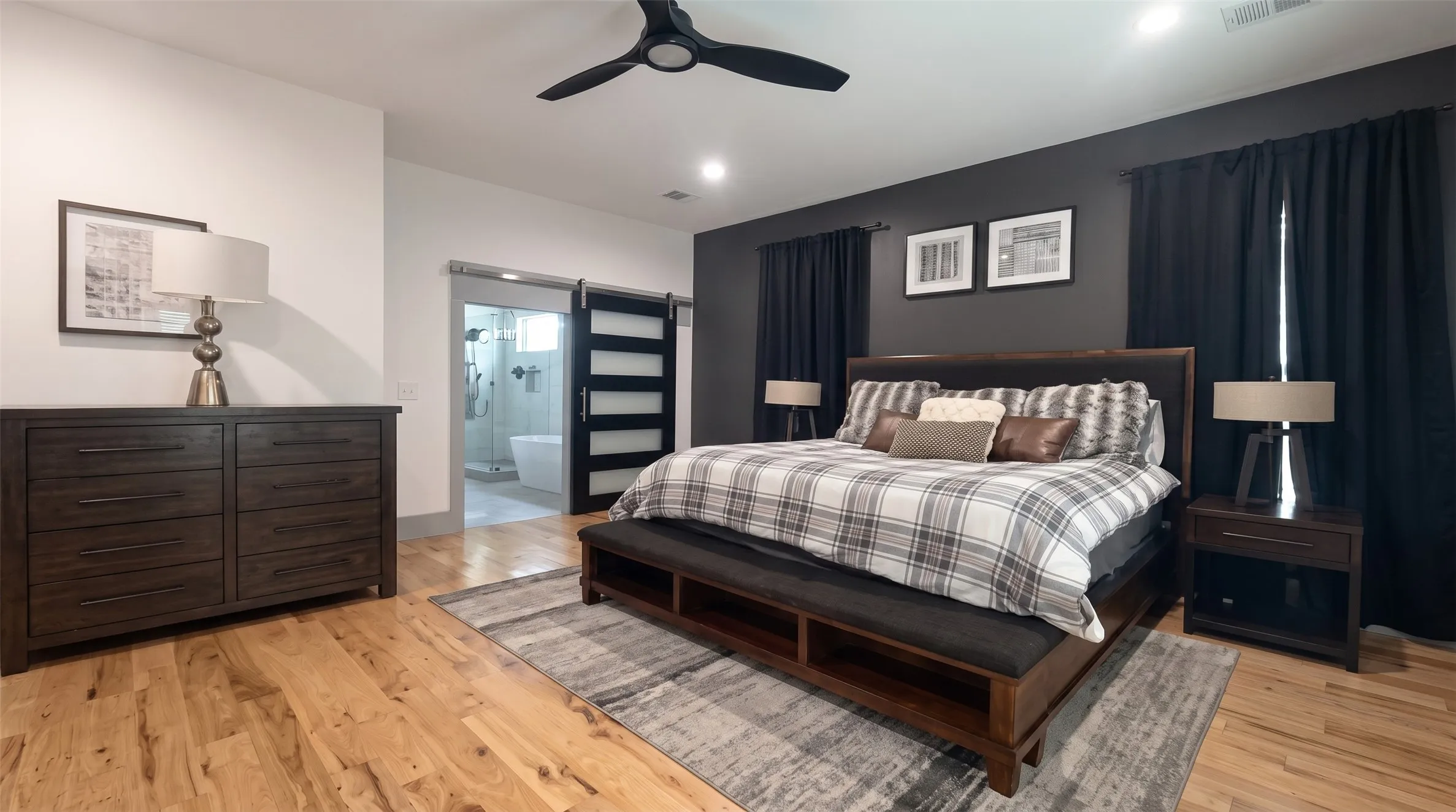 Hardwood flooring, recessed lighting, ceiling fan, dark accent wall, and a barn door entry