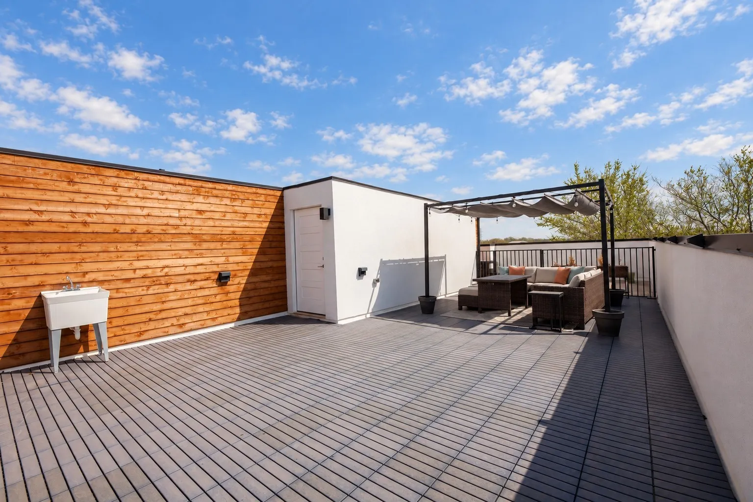Expansive rooftop deck featuring modular tile flooring, a wood-paneled wall, a utility sink, and a built-in outdoor structure with a retractable canopy