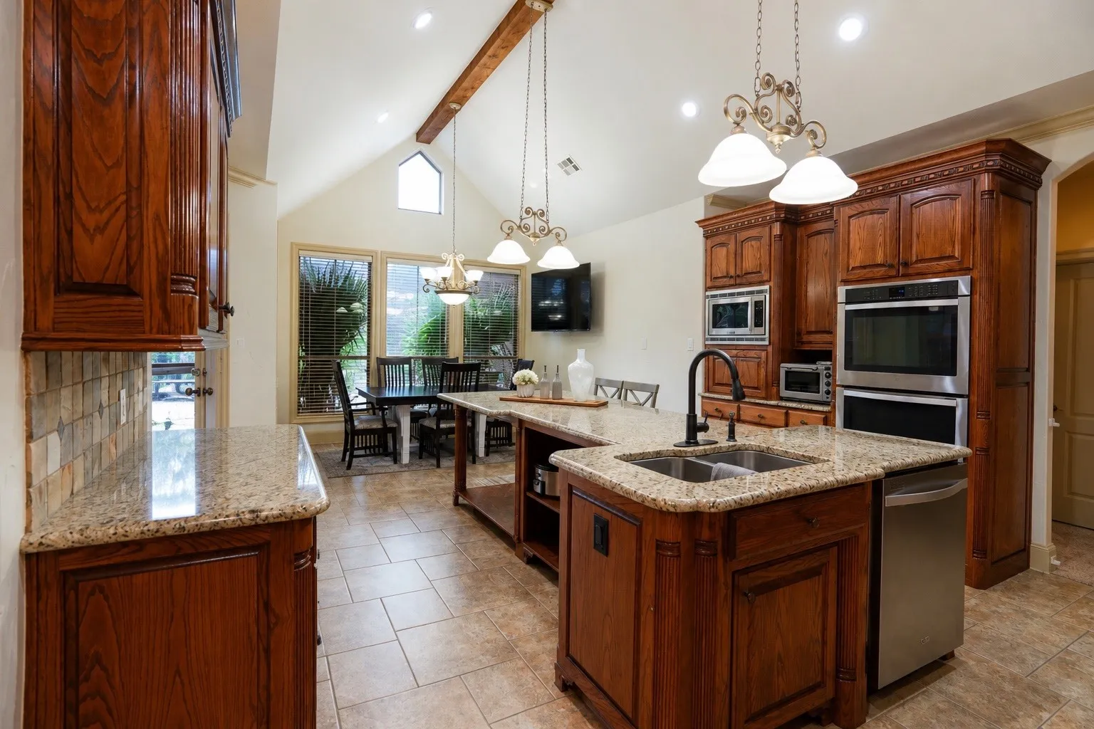 Kitchen featuring wood cabinetry, light-toned granite countertops, a built-in double oven, and a double basin sink
