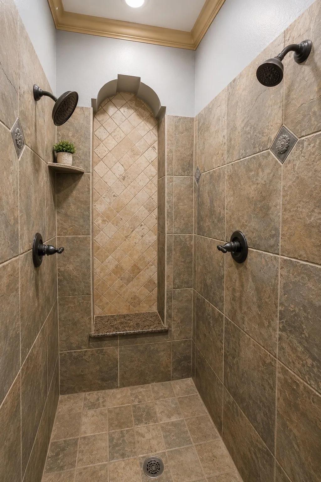 Tiled shower with multiple showerheads, a recessed niche, a built-in shelf, and crown molding