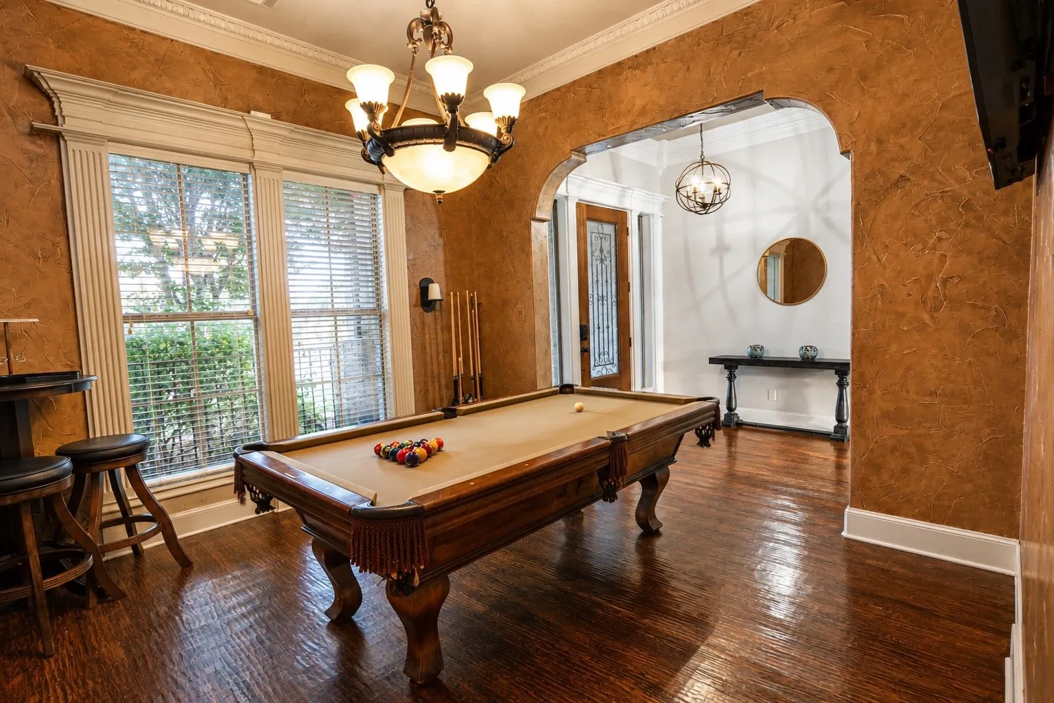 Rich wood-finish flooring, textured wall finishes, and an arched entryway