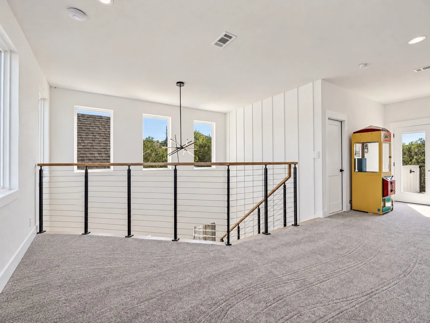 Carpeted loft space featuring a cable railing system, recessed lighting, and multiple windows