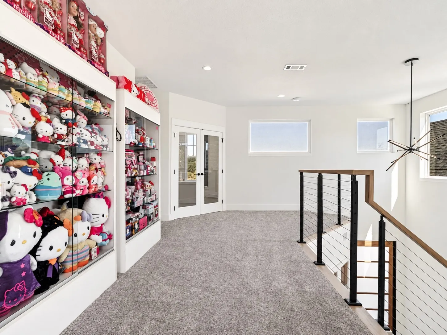 Bright upstairs landing with walnut handrails, cable railing, and distinctive lighting overlooking the foyer below.