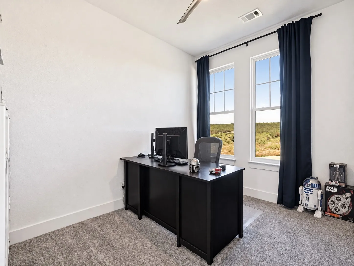 Dedicated office with two tall windows, hillside views, and ample space behind glass french doors.