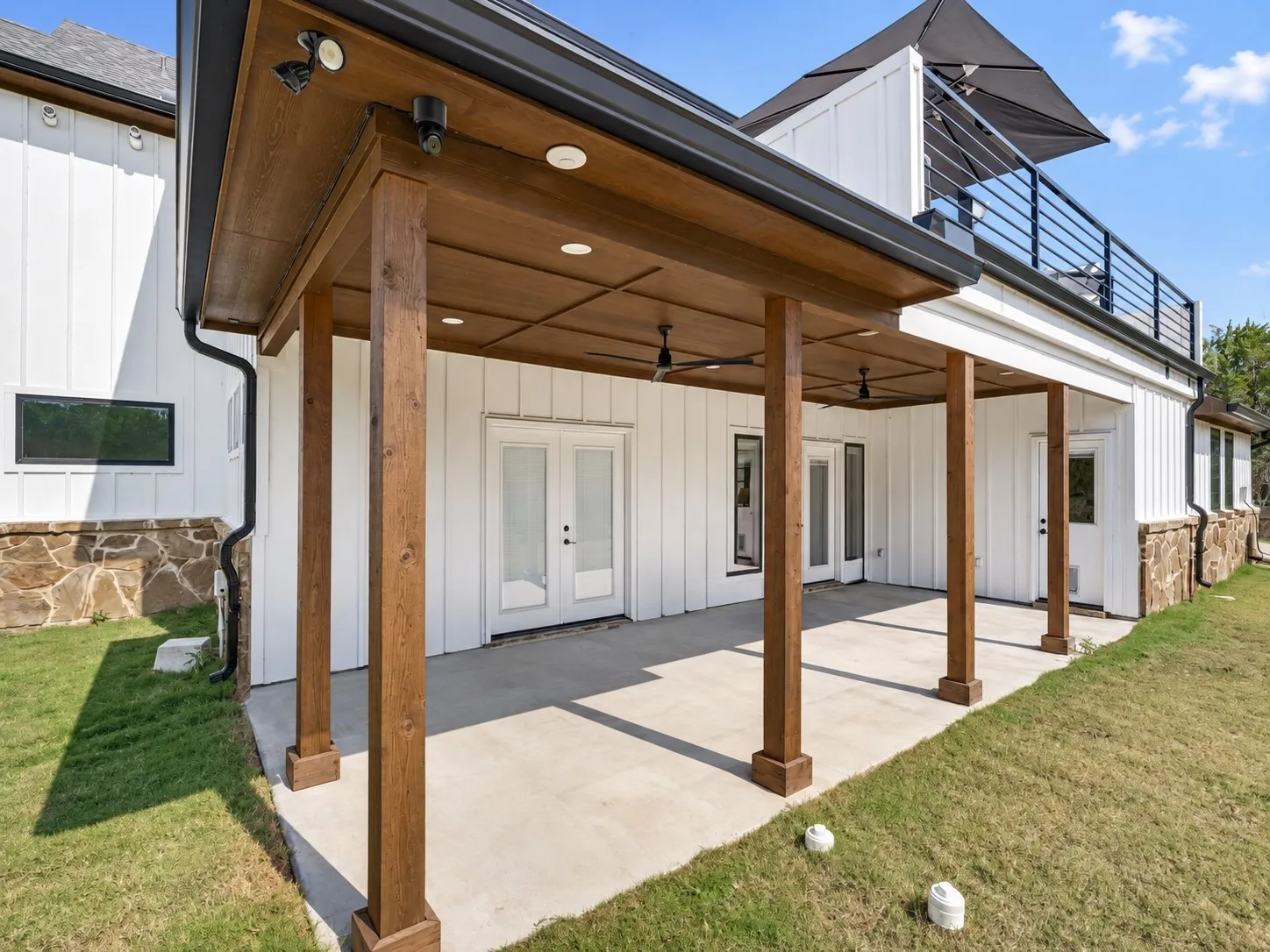 Covered rear patio features rich wood beams, a wood-paneled ceiling, and ceiling fans, with walk out access from the primary, great room and utility rooms.