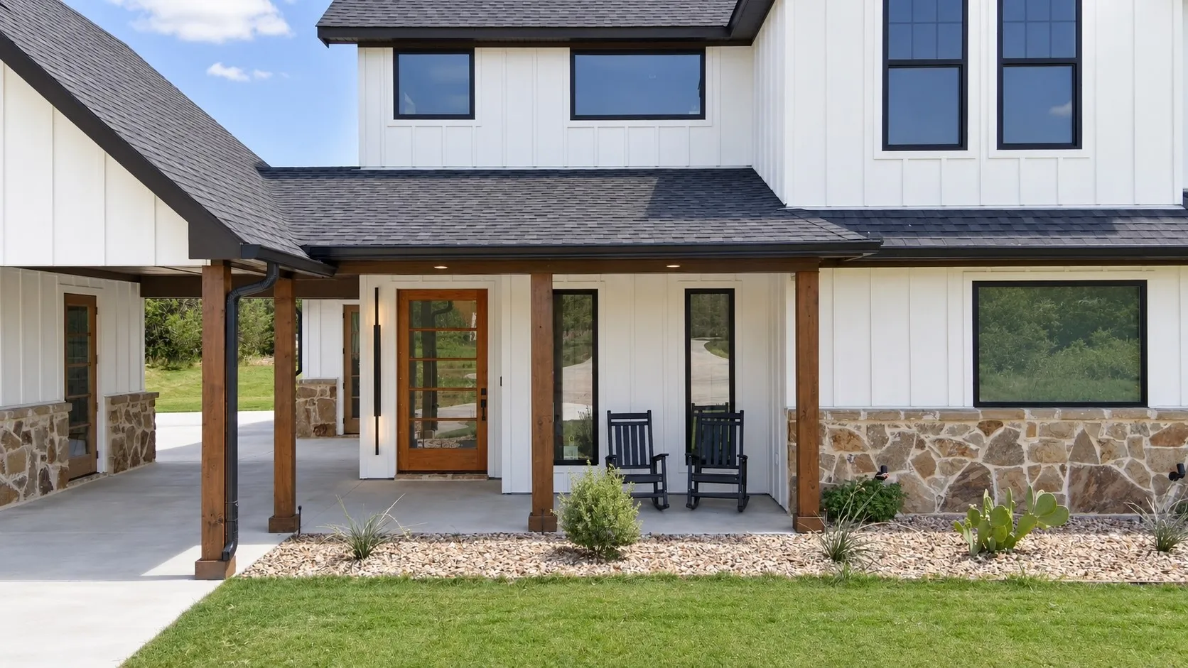 Rich wood posts, stone accents, and a welcoming covered front porch complement the home’s crisp white farmhouse exterior.