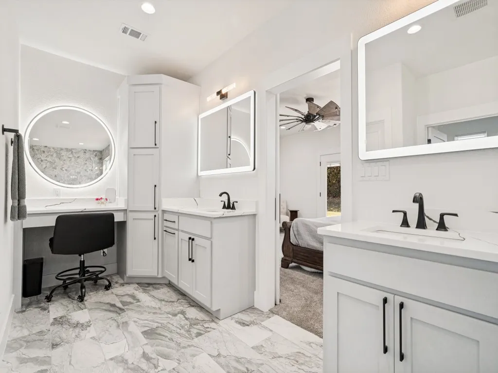 Dual vanities with integrated lighting mirrors, white shaker cabinetry, quartz countertops, and matte black fixtures