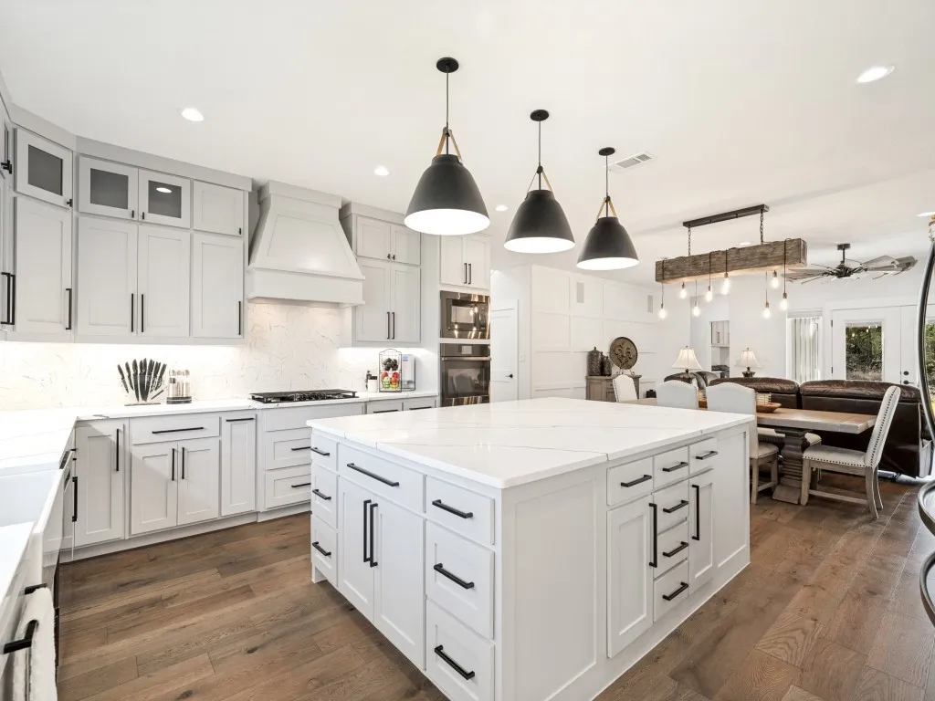 Expansive kitchen island with a light-toned countertop, shaker-style cabinetry, and wood-finish flooring
