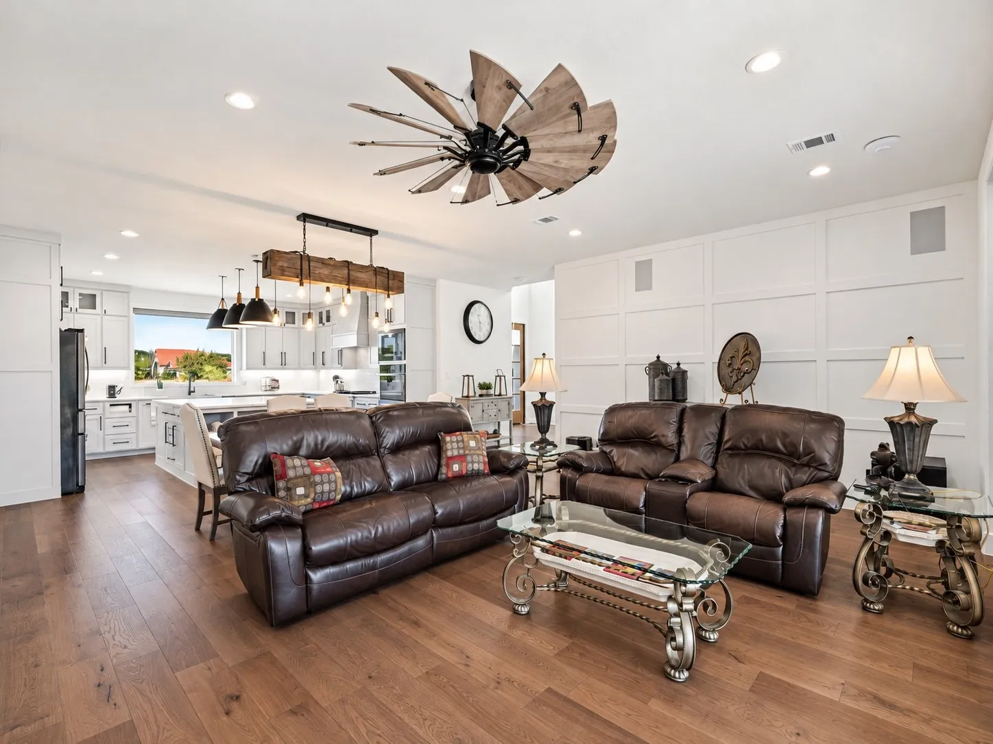 Expansive living area with wood-finish flooring, recessed lighting, and a decorative ceiling fan