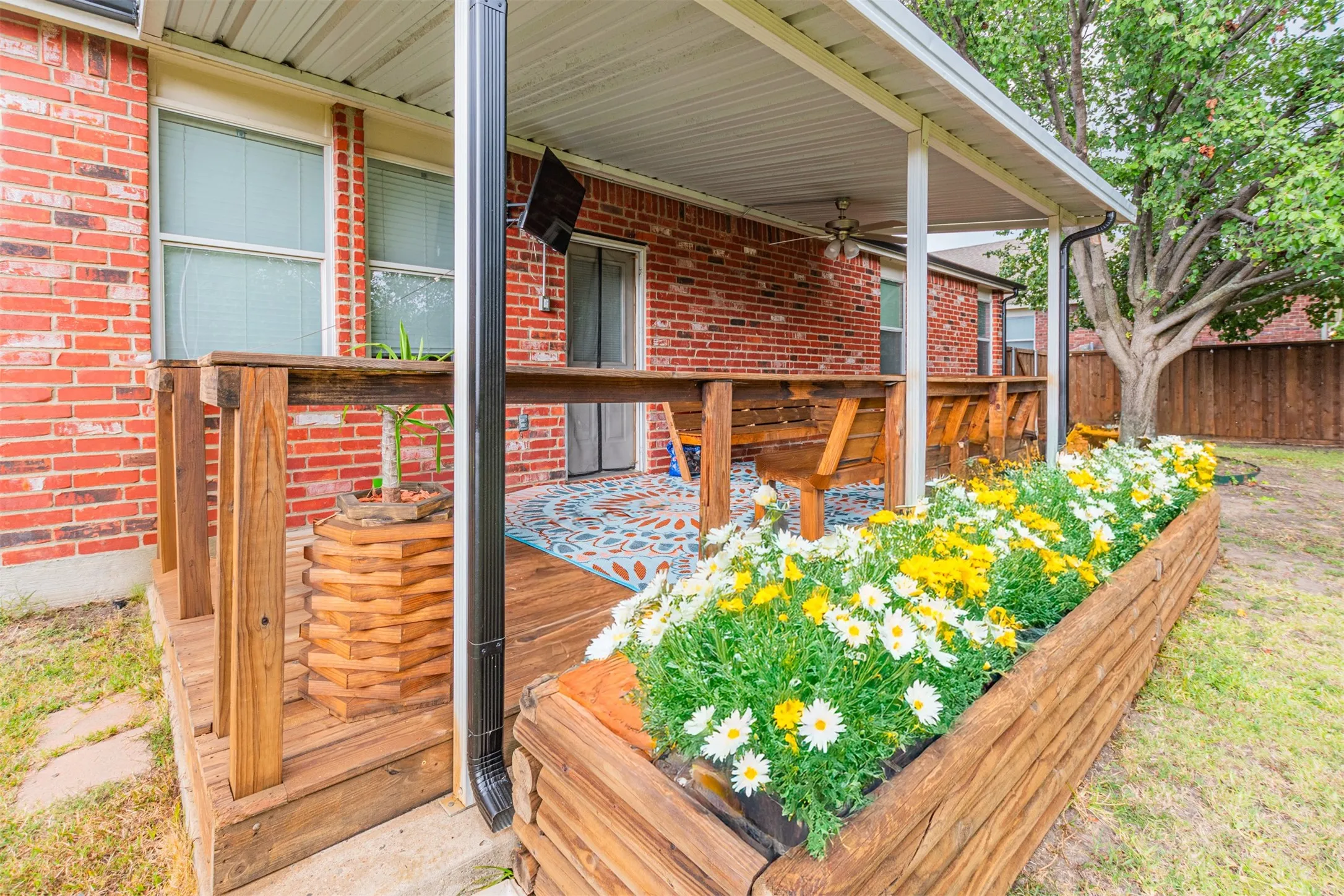 Brick exterior with a covered patio, wood deck, and built-in wood benches
