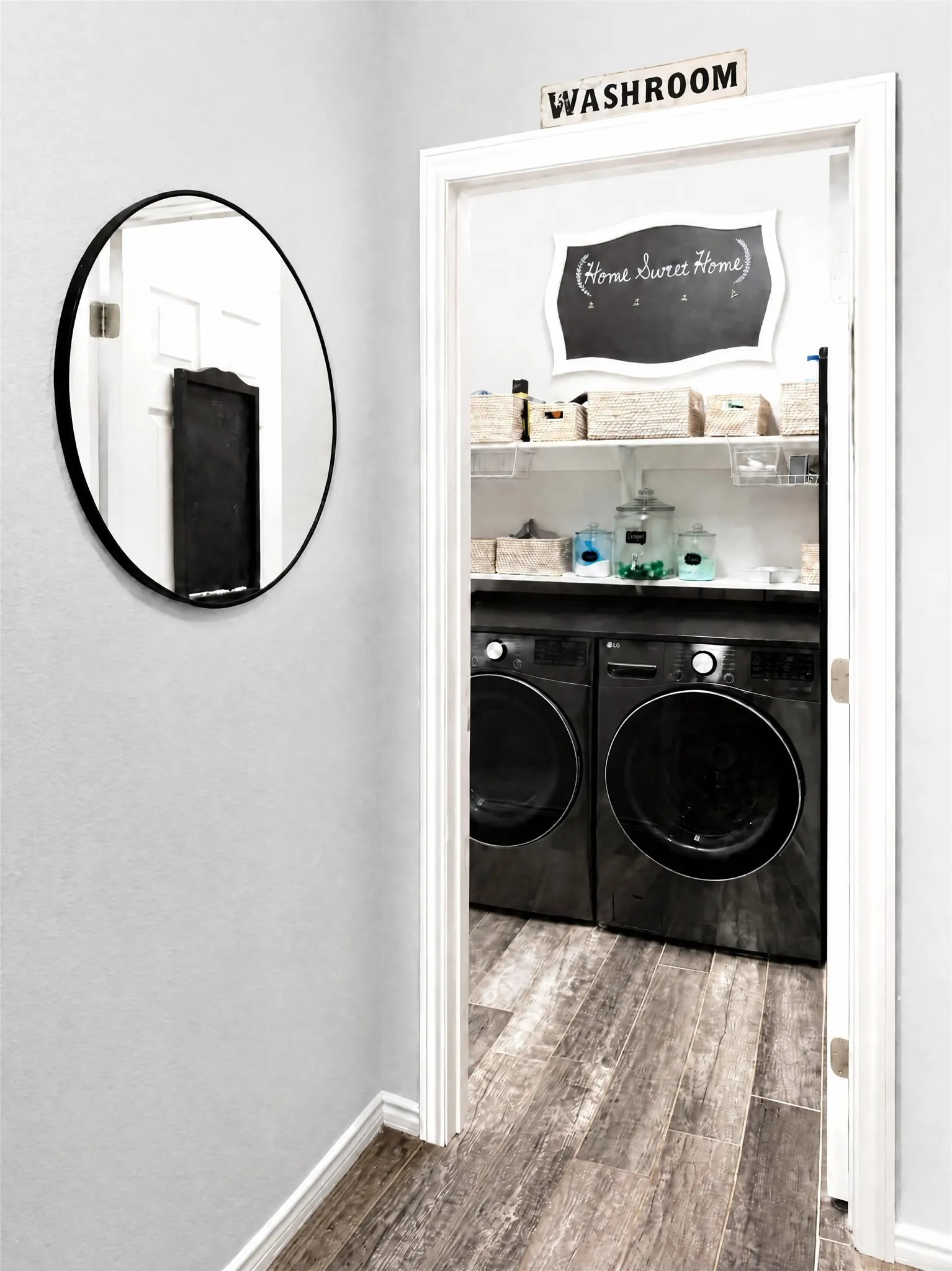 Dedicated laundry area featuring wood-finish flooring, built-in shelving, and white trim