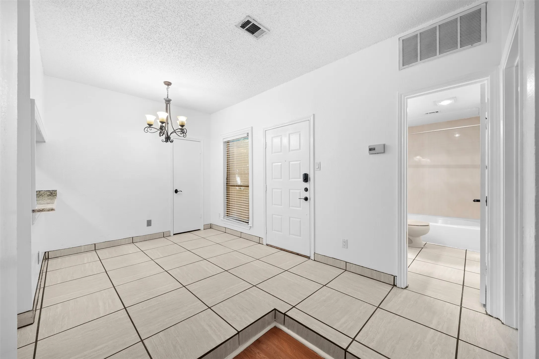 Recessed lighting, tile flooring, window with blinds, paneled interior door, and a built-in shelf with a stone-finish countertop