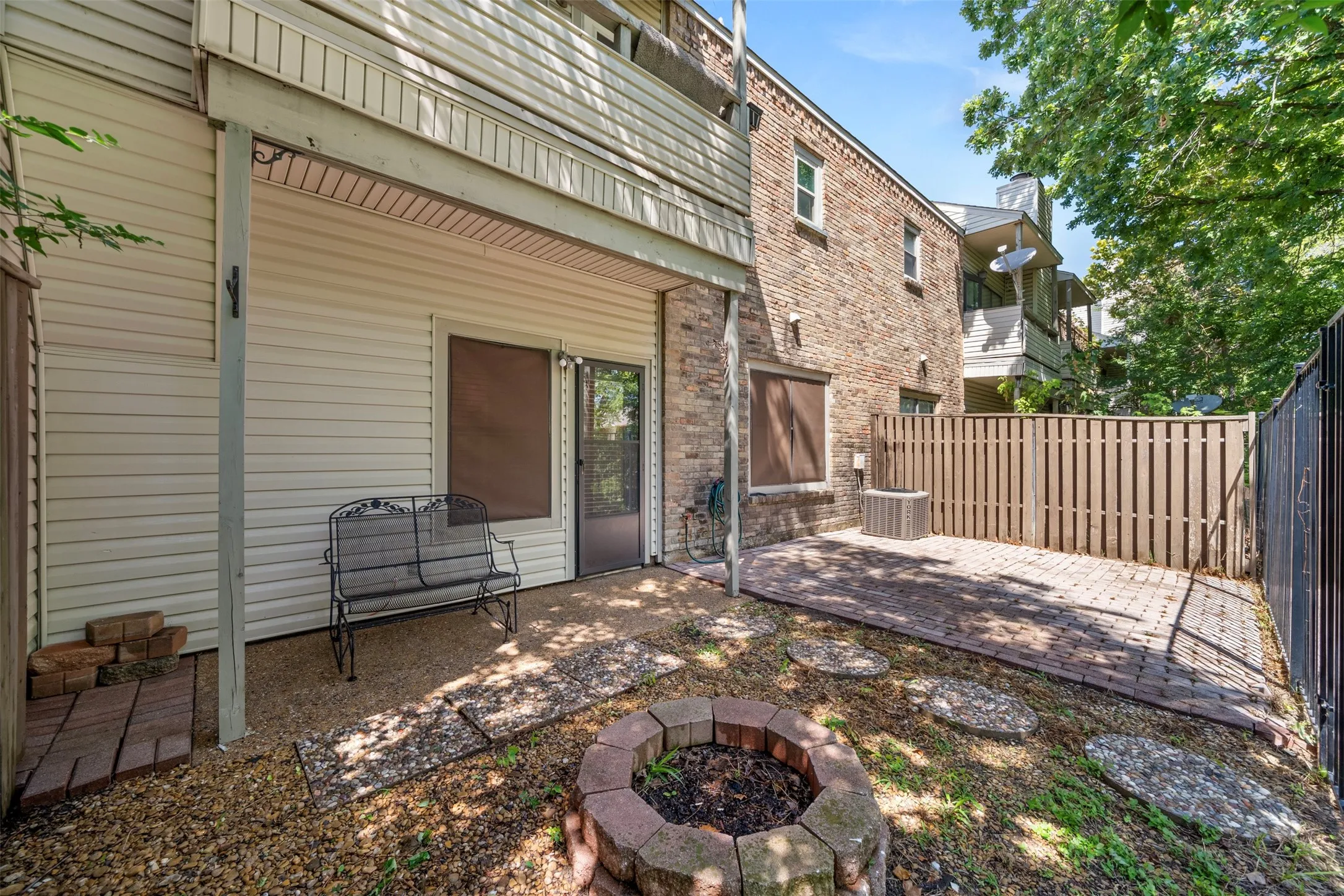 Rear patio with brick pavers, fire pit, and privacy fencing