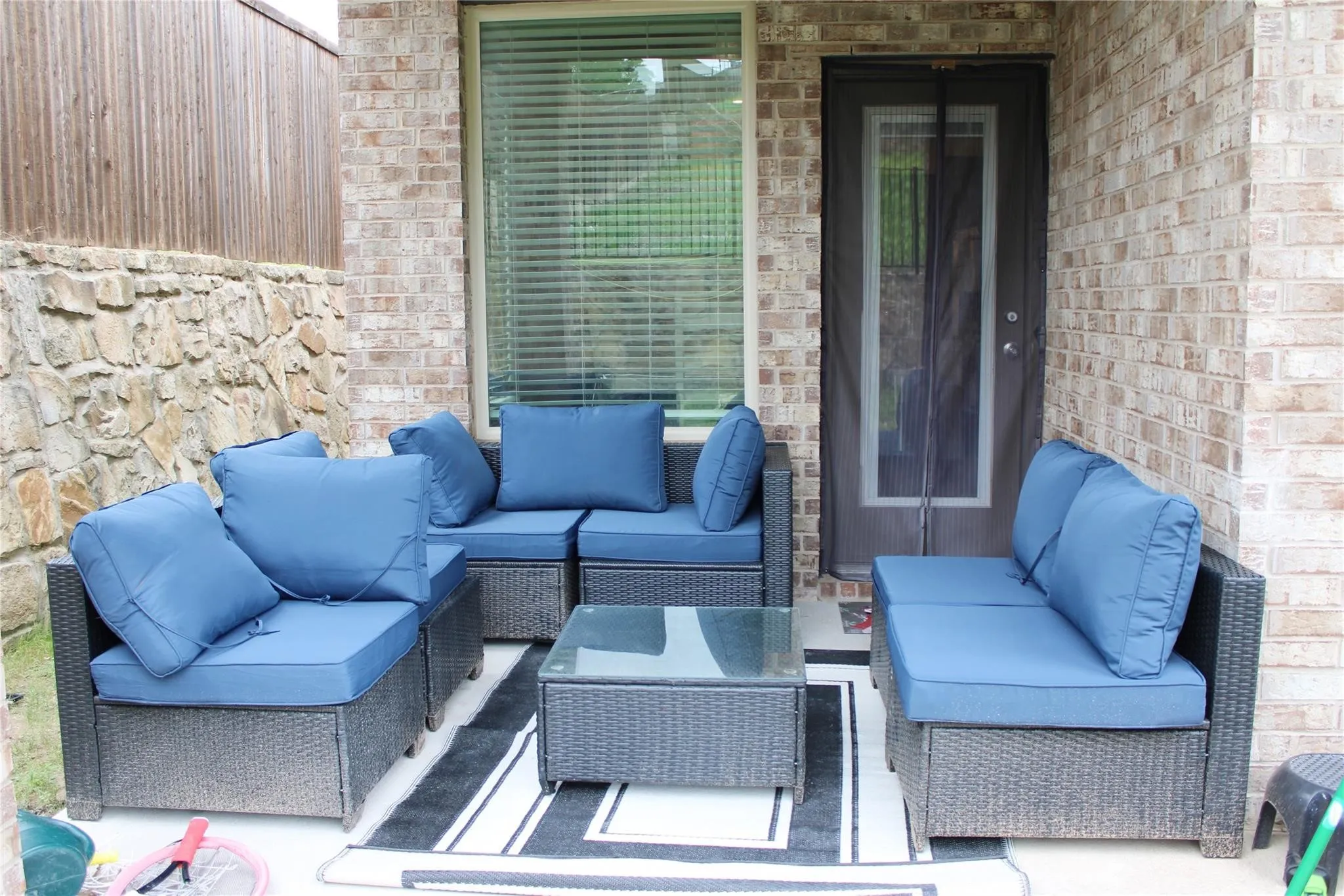 Brick exterior wall, covered patio, stone retaining wall, and horizontal wood fencing