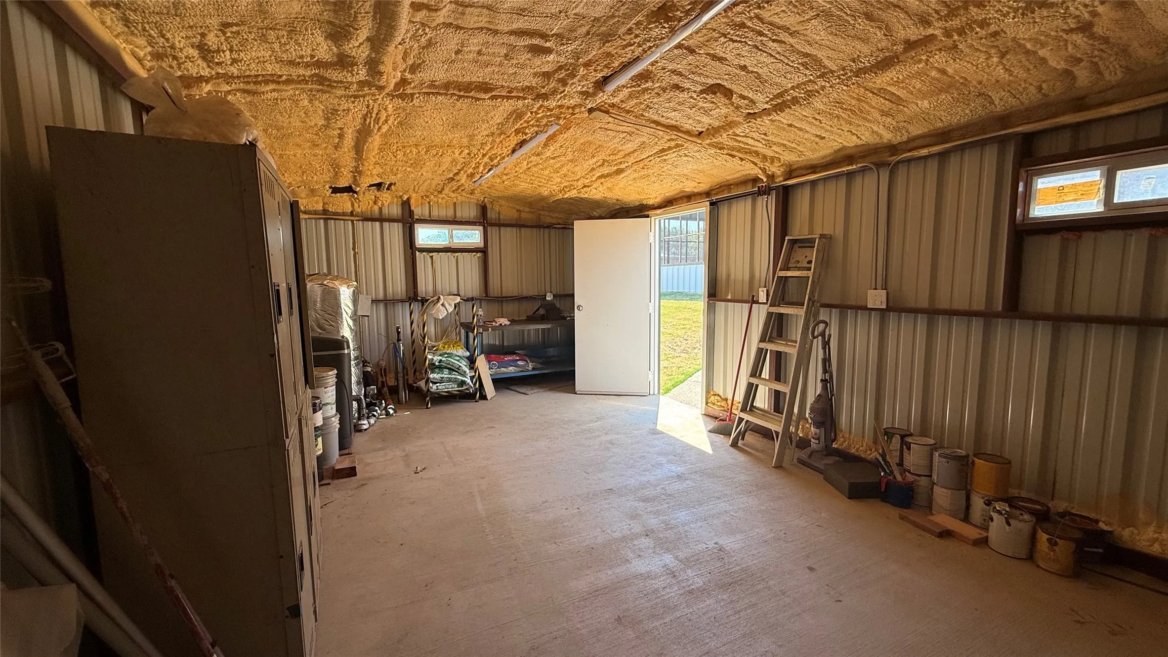 Metal-sided interior with concrete flooring and spray foam insulation on the ceiling