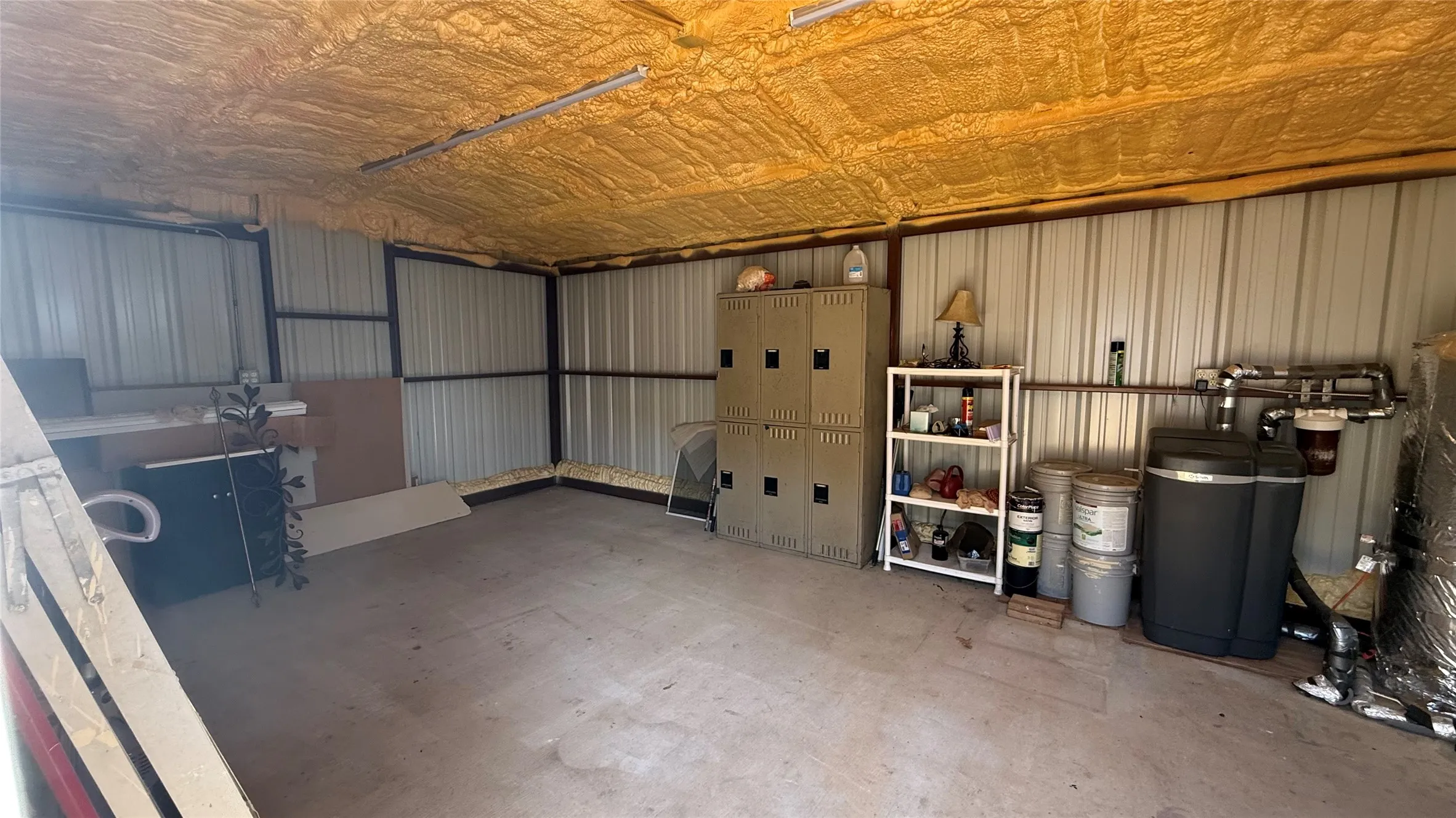 Insulated metal building featuring a concrete floor, exposed metal framing, and fluorescent lighting