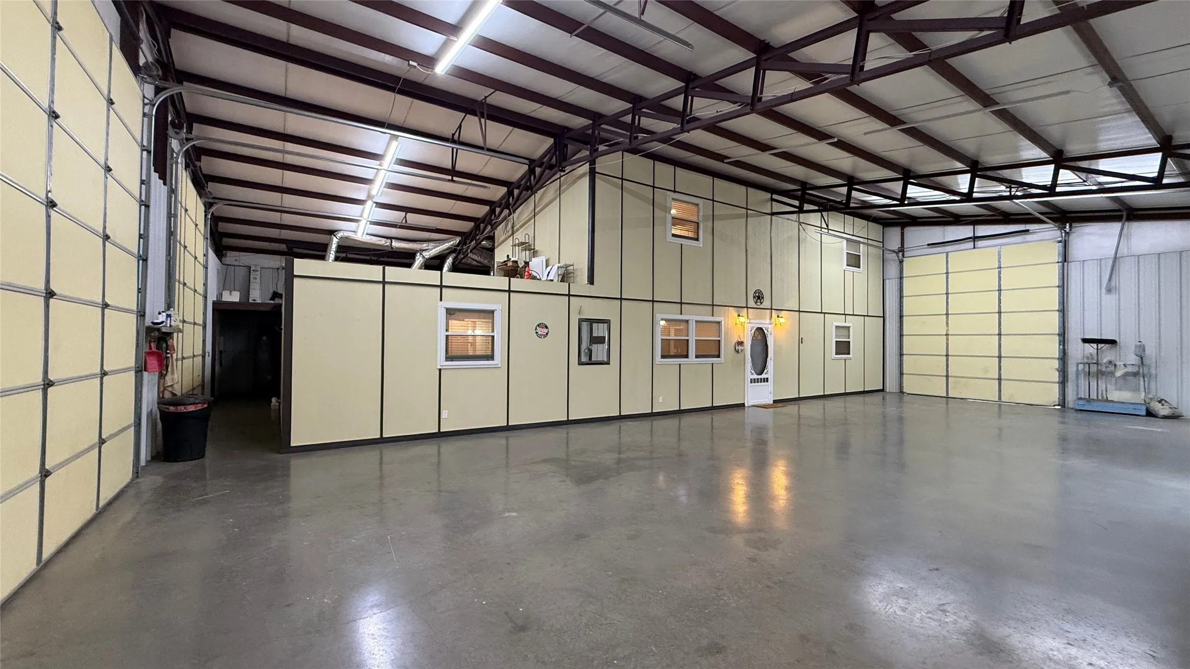 Spacious interior with polished concrete flooring, exposed metal beam ceiling, and multiple overhead doors