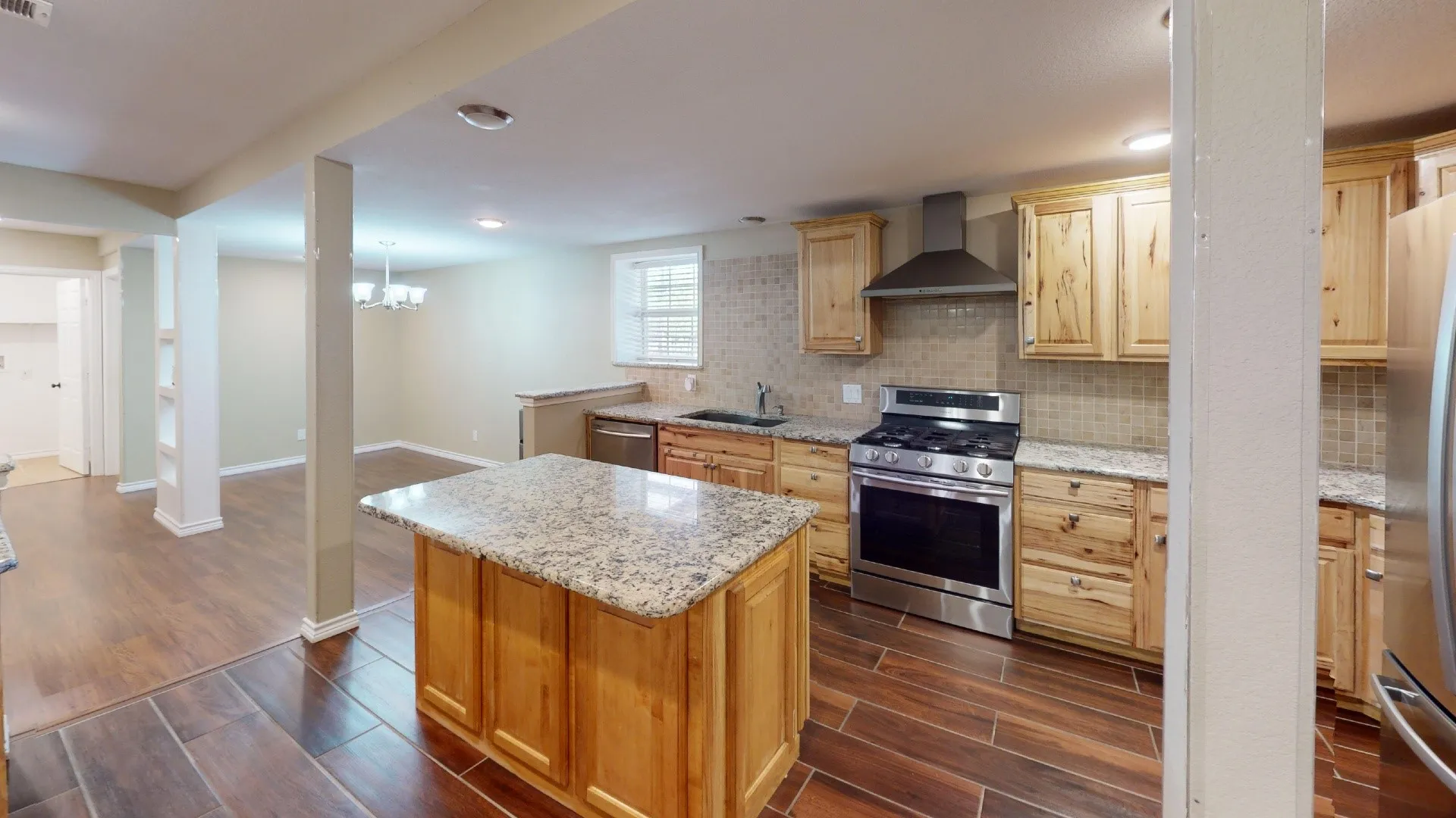 Kitchen featuring a center island with a granite countertop, wood cabinetry, stainless steel appliances, and a tiled backsplash