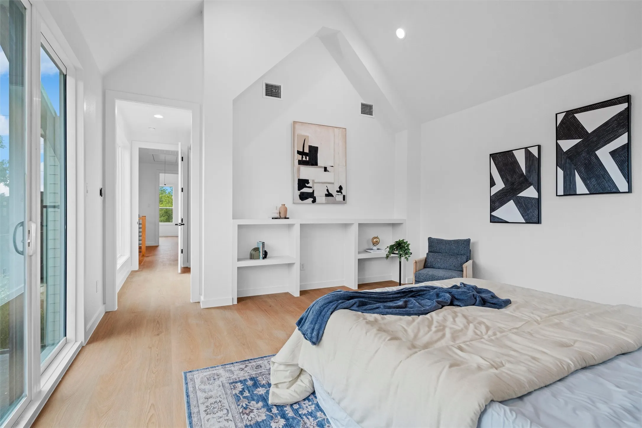Vaulted ceiling bedroom with light wood-finish flooring, built-in shelving, and recessed lighting