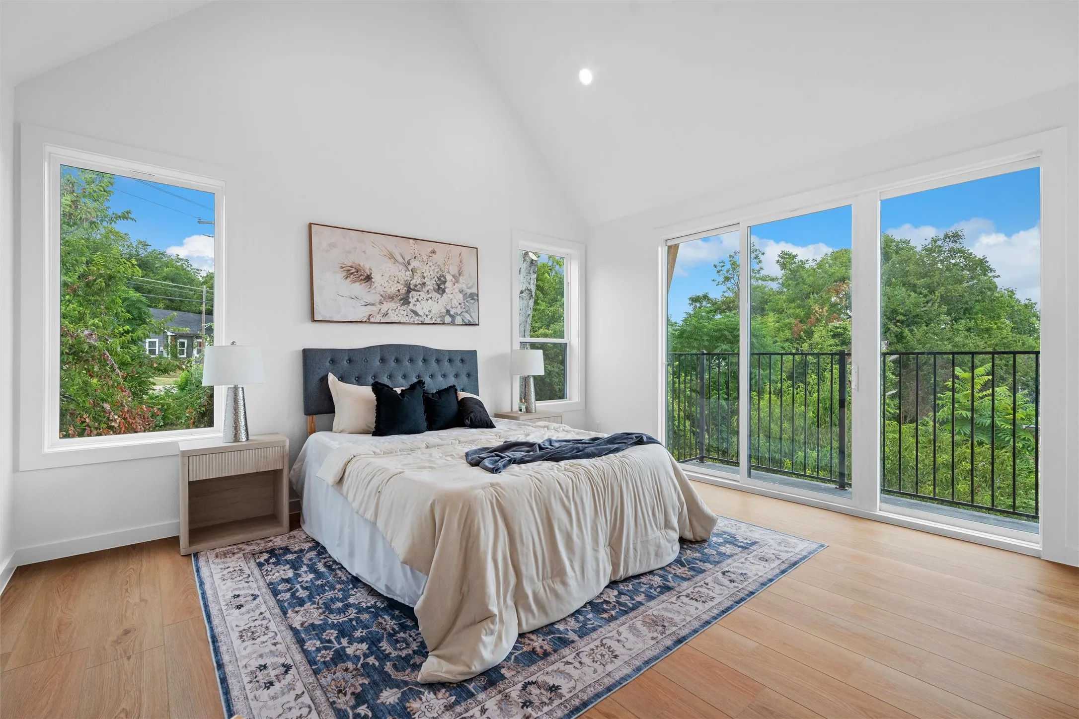 Spacious room featuring wood-finish flooring, a vaulted ceiling, and multiple large windows