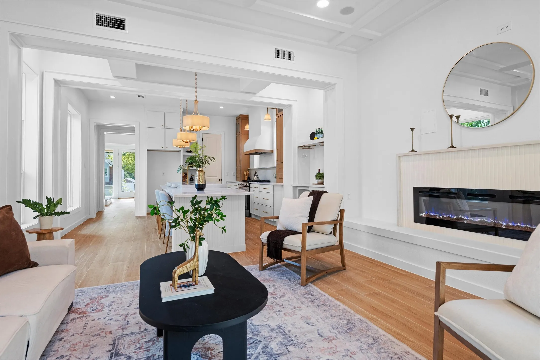 Open-concept living area featuring wood-finish flooring, a contemporary fireplace, and recessed lighting