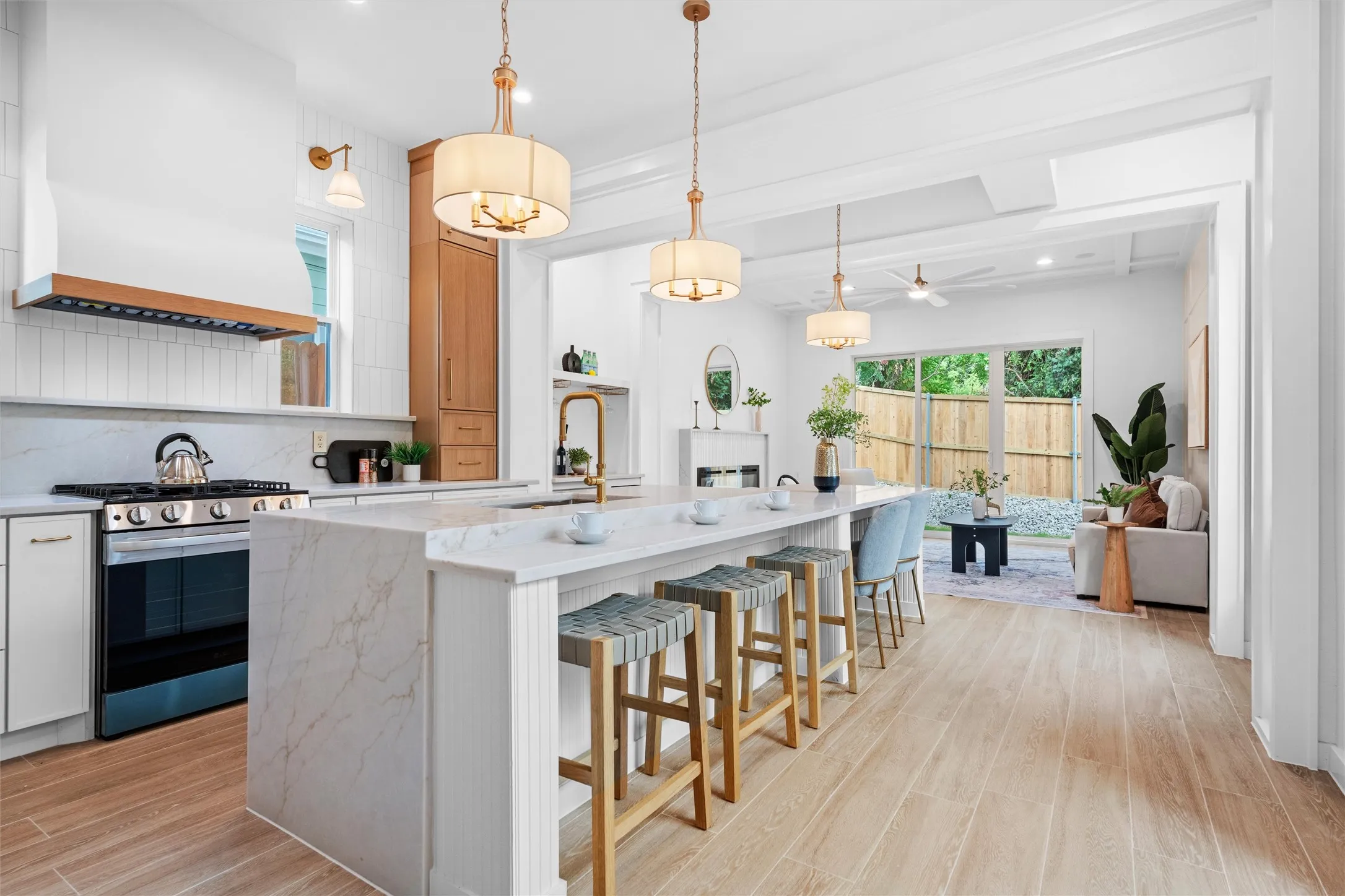 Open-concept kitchen featuring a large waterfall island with seating, stainless steel appliances, and wood-finish flooring