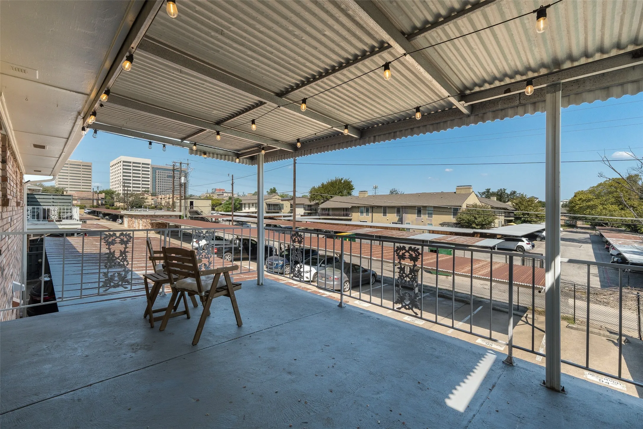 Covered balcony with string lighting, concrete flooring, and metal railings