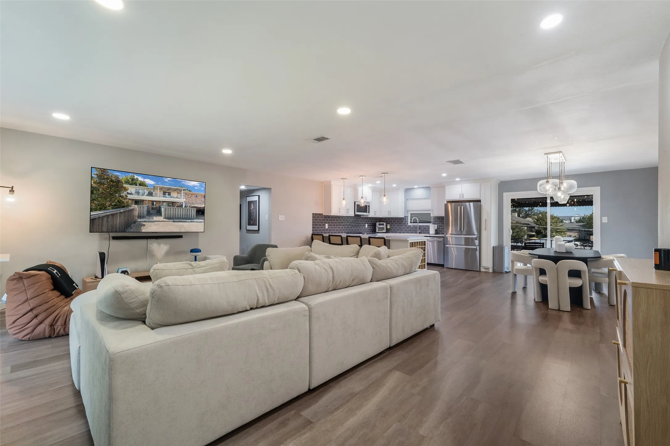 Open-concept living space featuring wood-finish flooring, recessed lighting, and a kitchen with stainless steel appliances