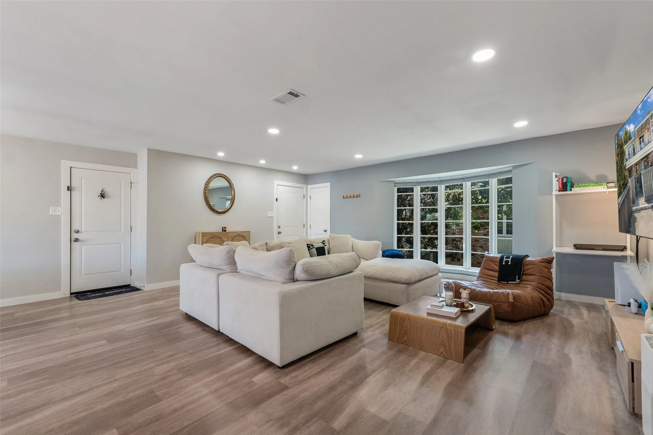 Recessed lighting, wood-finish flooring, bay window, built-in shelving, and a paneled entry door
