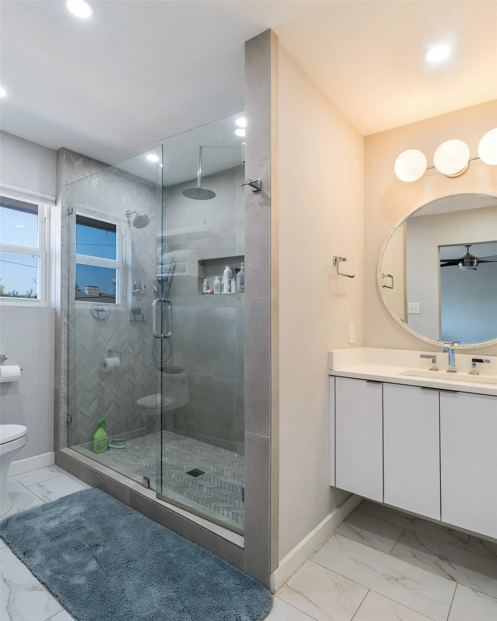 Glass-enclosed shower with a recessed shelf, dual shower heads, and patterned tile flooring
