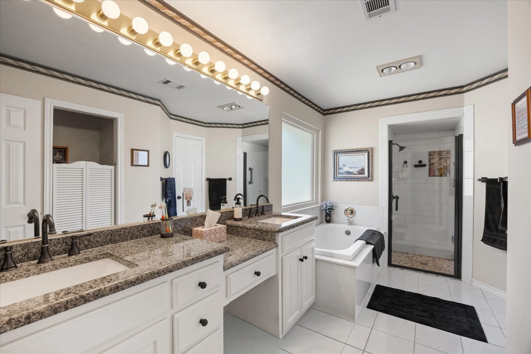 Dual vanity with undermount sinks, granite countertops, and white cabinetry