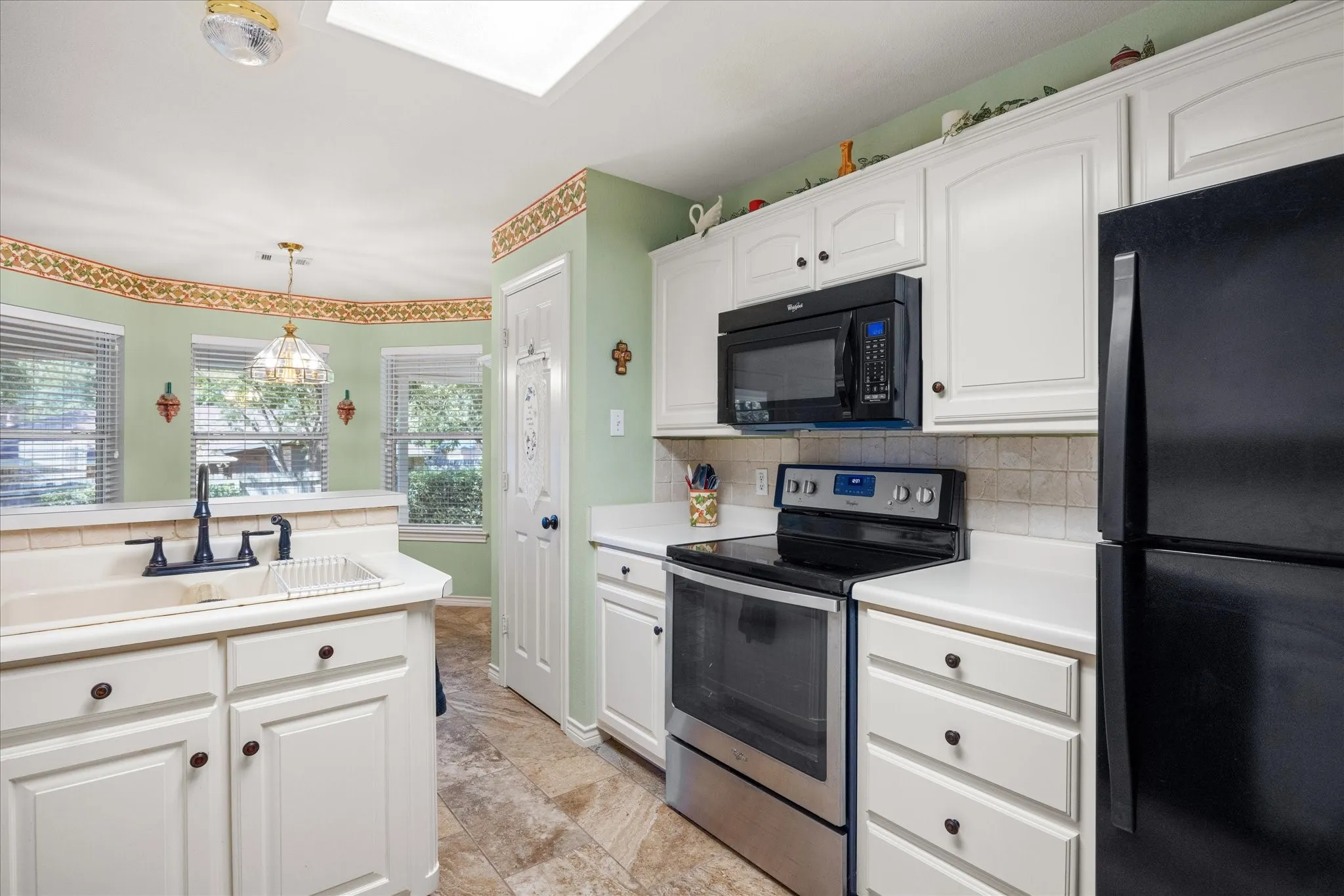 Kitchen featuring white cabinetry, black appliances, a built-in microwave, and tile flooring