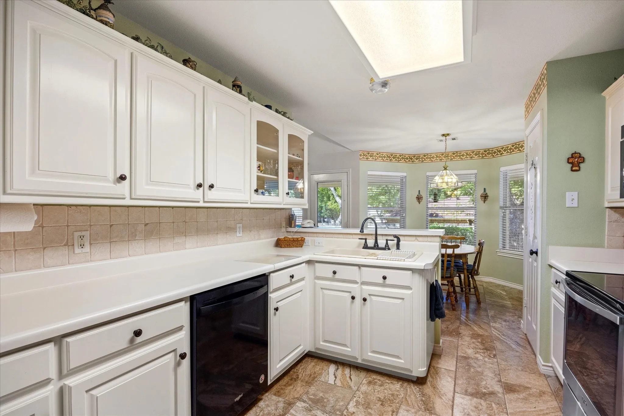 White cabinetry with dark hardware, a tile backsplash, and a built-in dishwasher