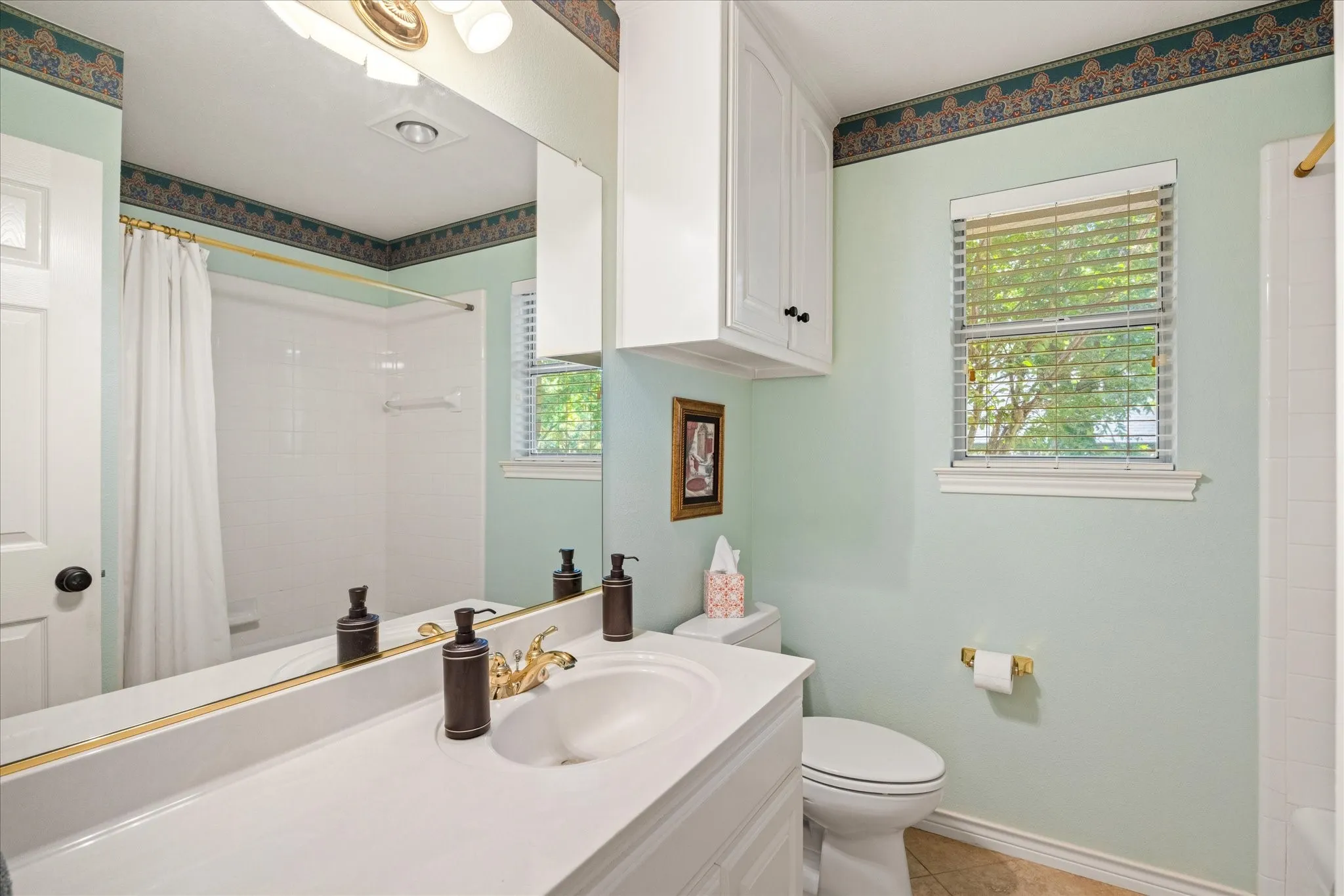 Spacious vanity with an integrated sink, polished brass faucet, and an expansive mirror