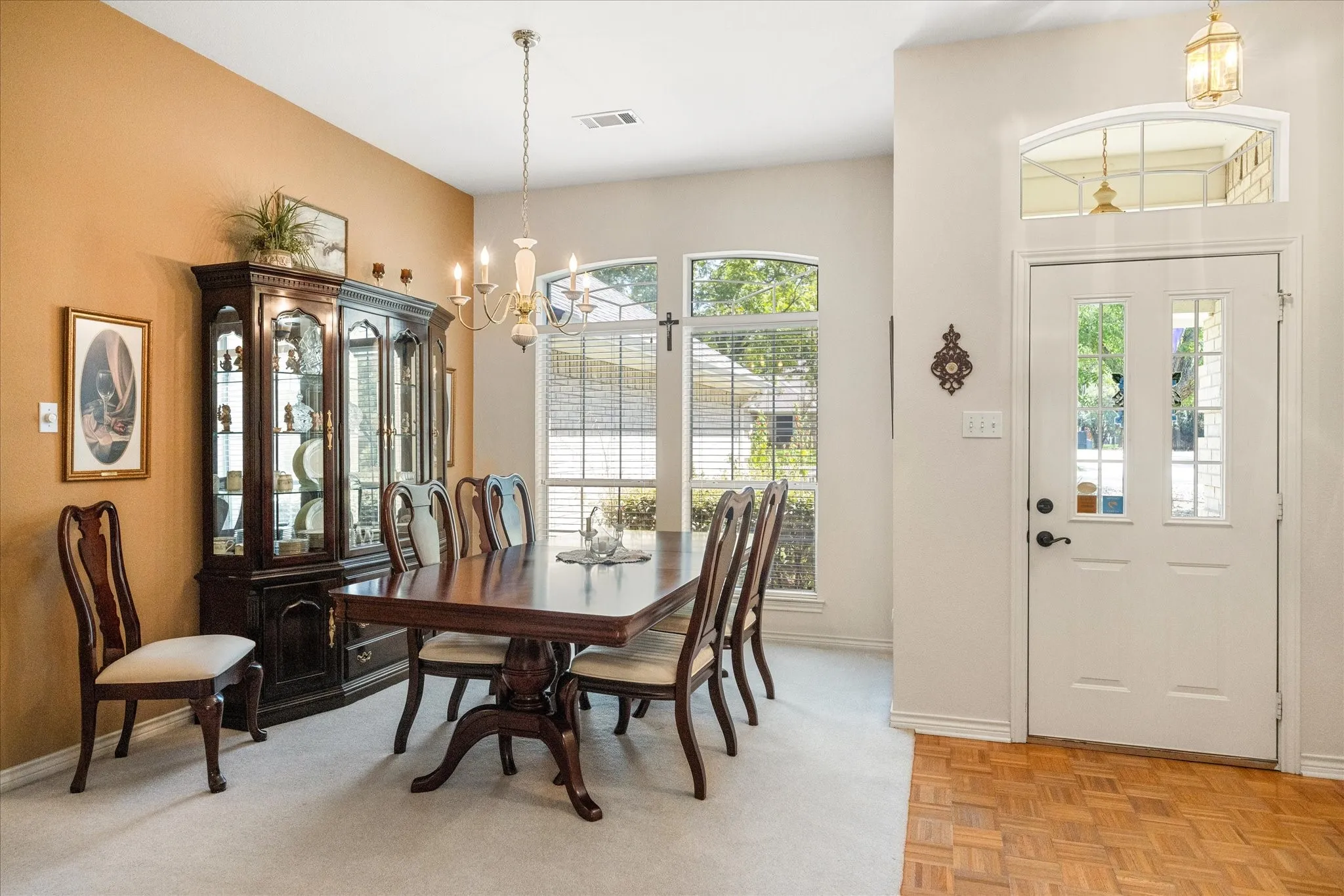 Carpeted flooring, arched windows, transom window, and a white paneled door with glass inserts