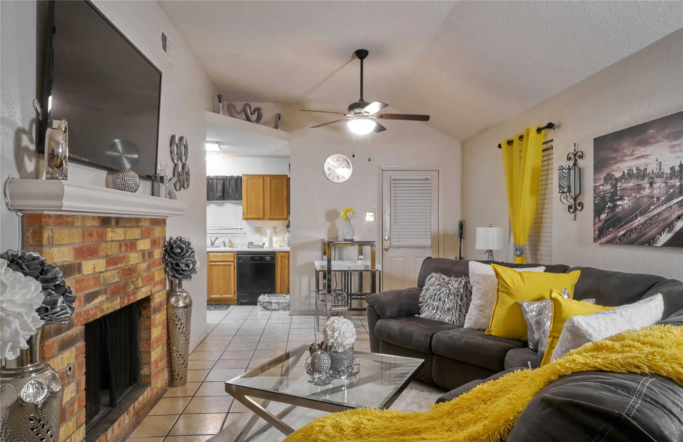 Tiled living room featuring ceiling fan, vaulted ceiling, a fireplace, and sink