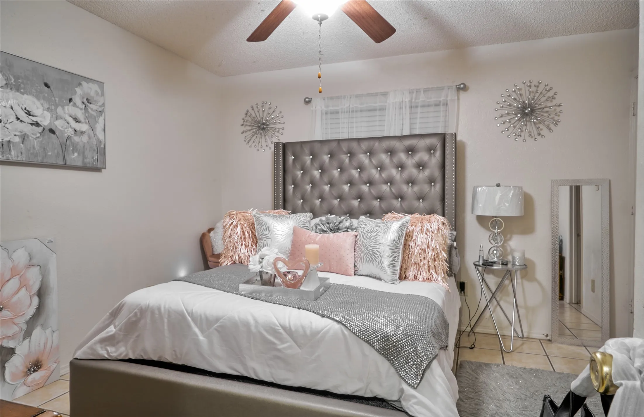 Tiled bedroom featuring ceiling fan and a textured ceiling
