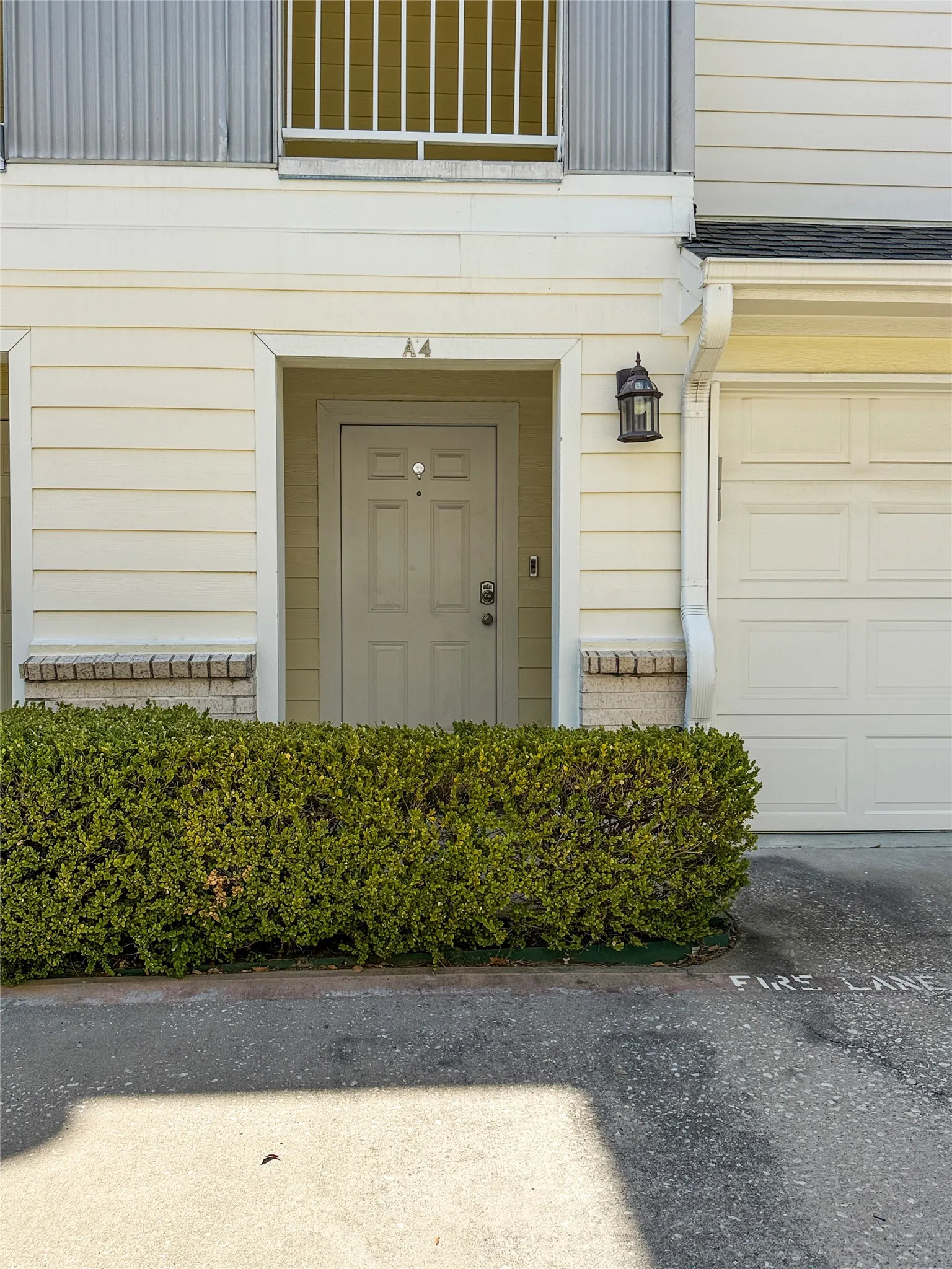 Siding exterior with brick detailing, a paneled entry door, an exterior wall lantern, and a segmented garage door