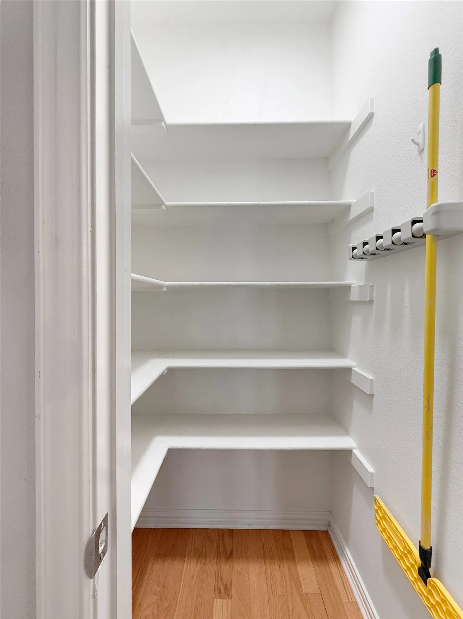 White built-in shelving, wood-finish flooring, and white painted walls