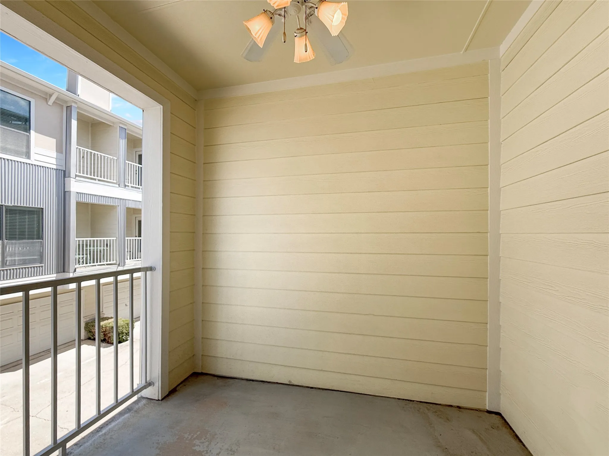 Private outdoor patio with a ceiling fan light fixture and a metal railing