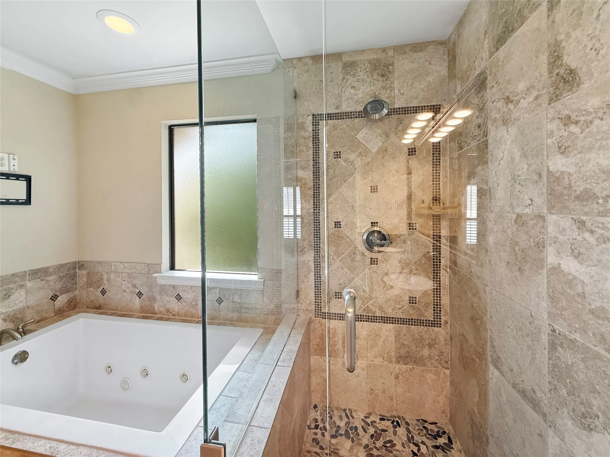 Jetted soaking tub, glass-enclosed shower with tiled walls, pebble shower floor, and recessed lighting
