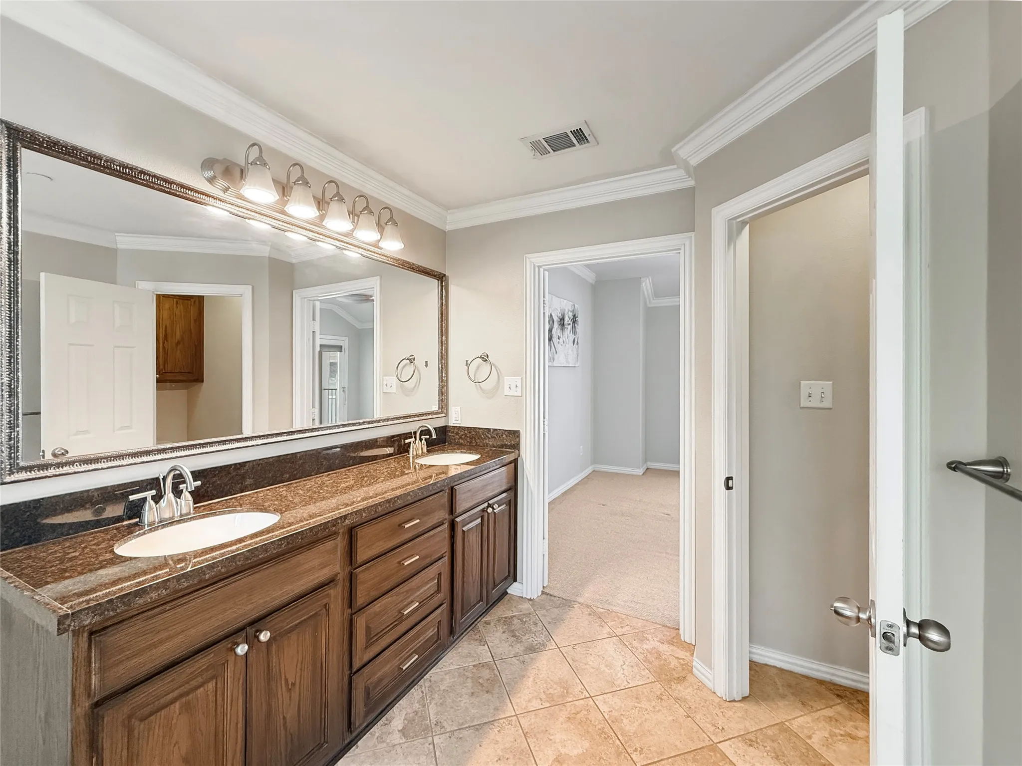 Double vanity with two undermount sinks, brown wood-finish cabinetry, and a dark countertop