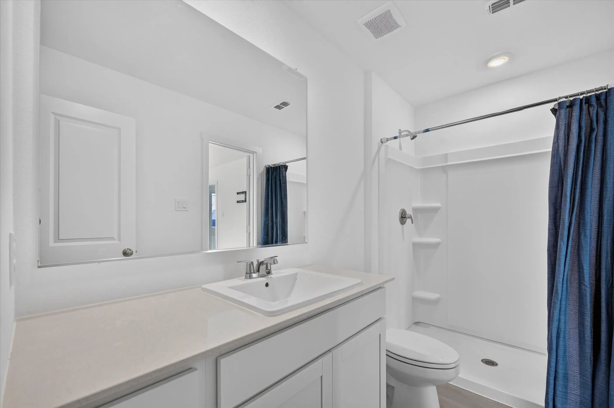 White vanity with integrated sink, light-colored countertop, and a chrome faucet