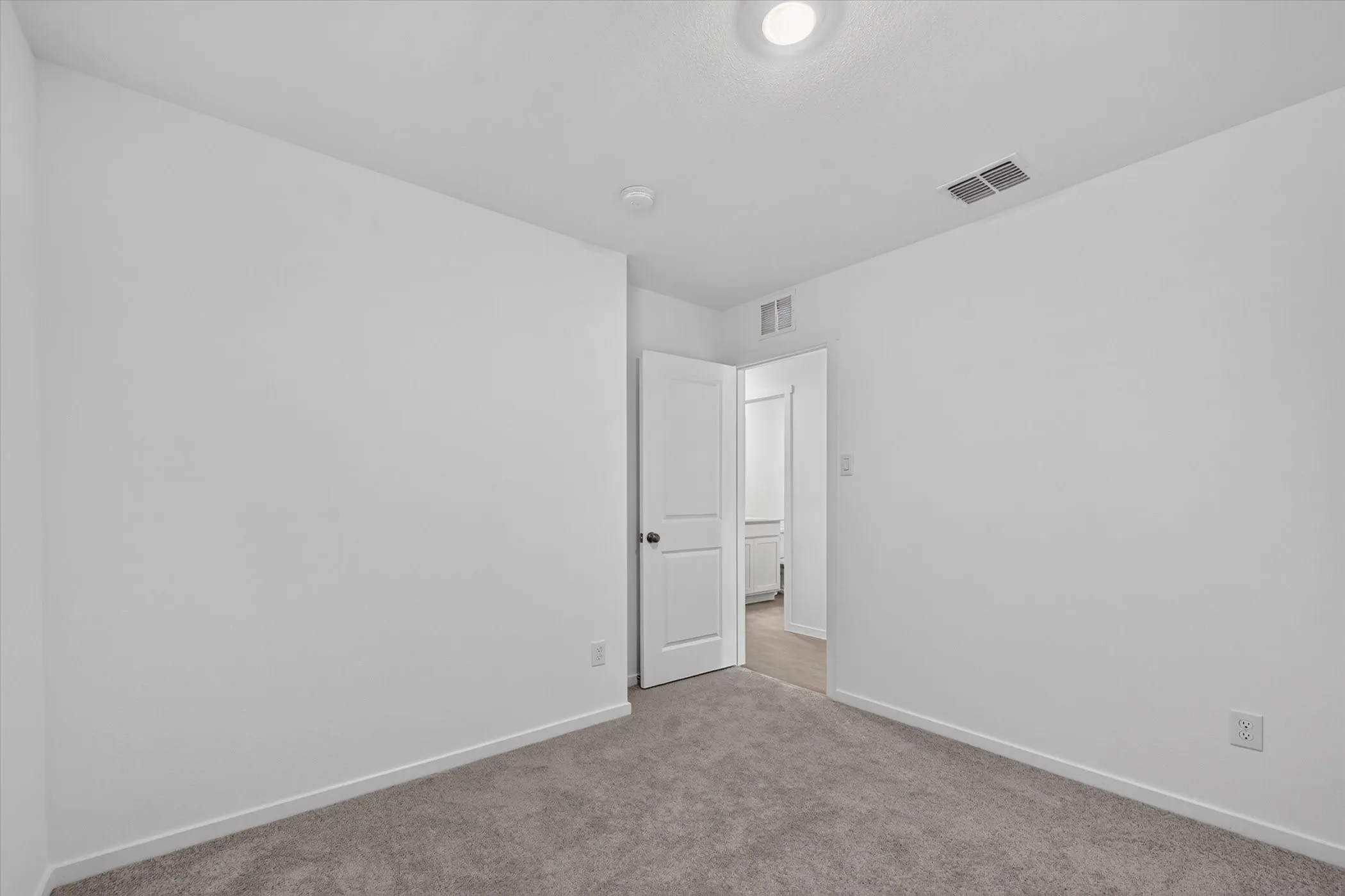 Recessed ceiling light, carpet flooring, and a white interior door