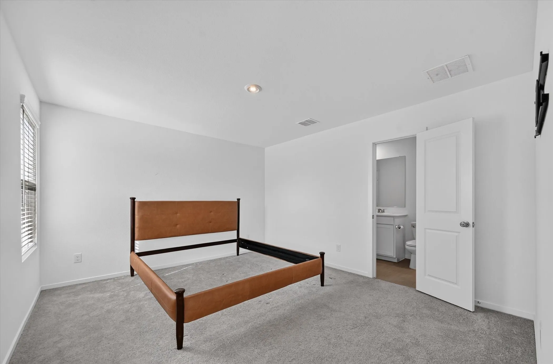 White walls, recessed lighting, and a window with blinds