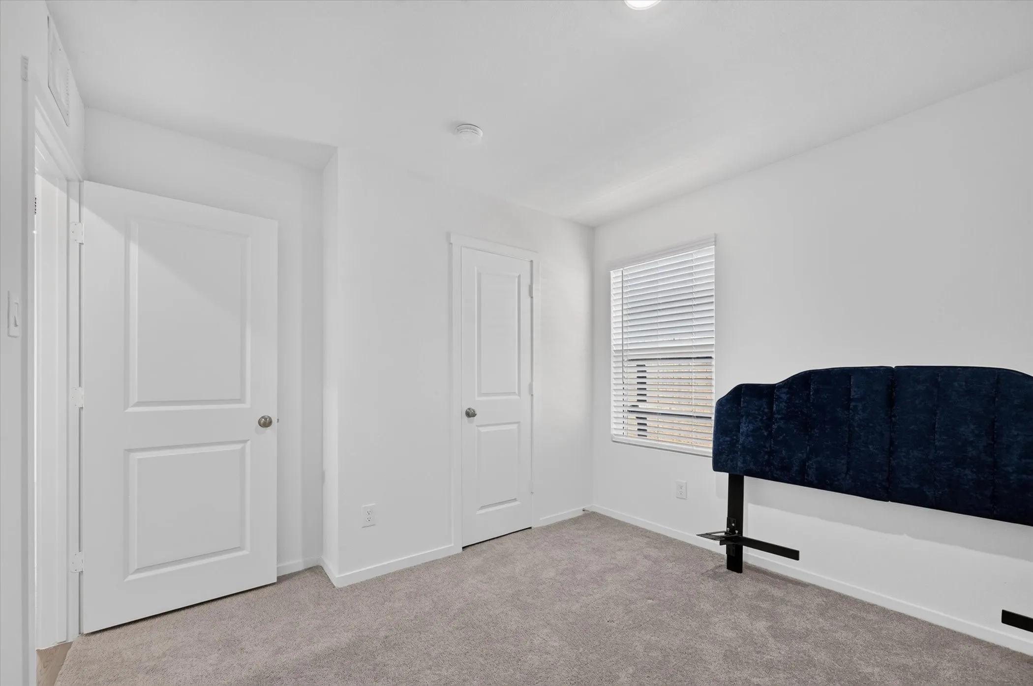 Carpeted room with a window featuring horizontal blinds