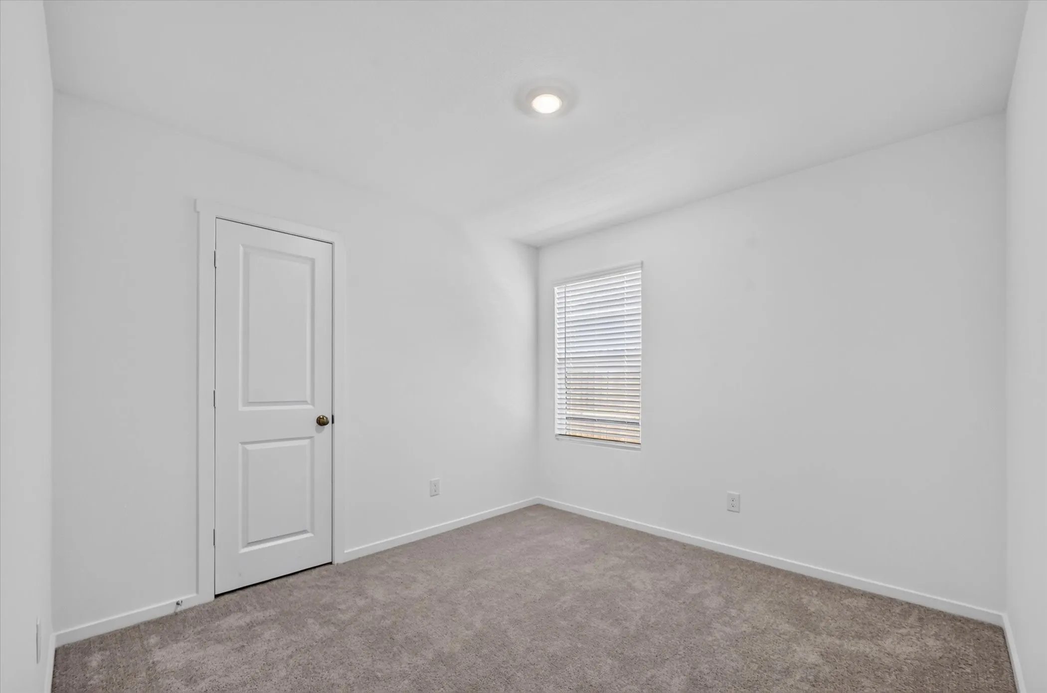 Recessed lighting, neutral wall paint, gray carpet flooring, window with horizontal blinds, and a paneled interior door