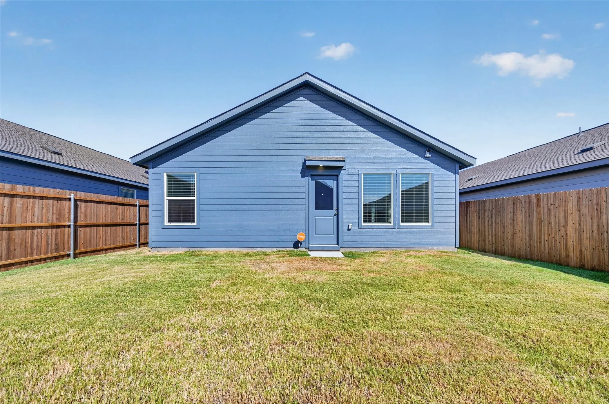 Expansive grassy yard with wood fencing and a blue exterior