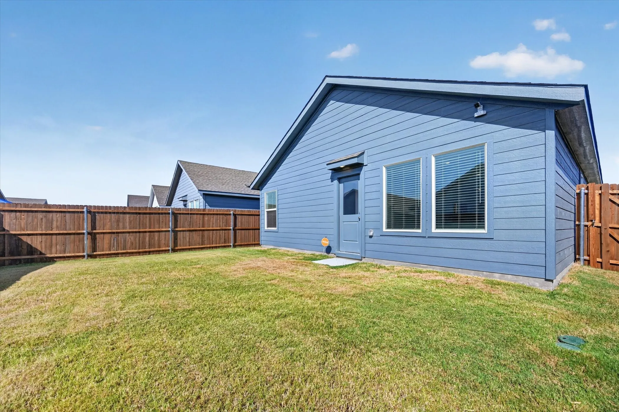 Expansive grassy yard with a wood privacy fence and a blue siding exterior